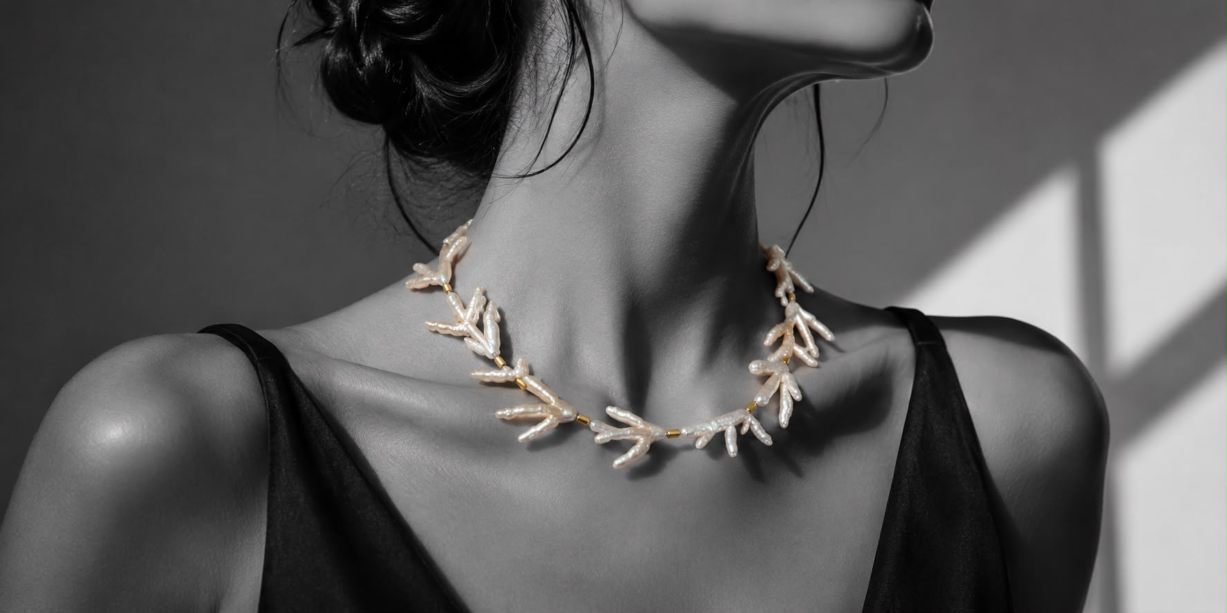 LUEL campaign portrait: black and white editorial photograph of a model wearing a handmade gold, pearl and coral necklace in natural colour